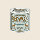 Candle in a tin labeled 'Redwood' with nature-themed design on a white background